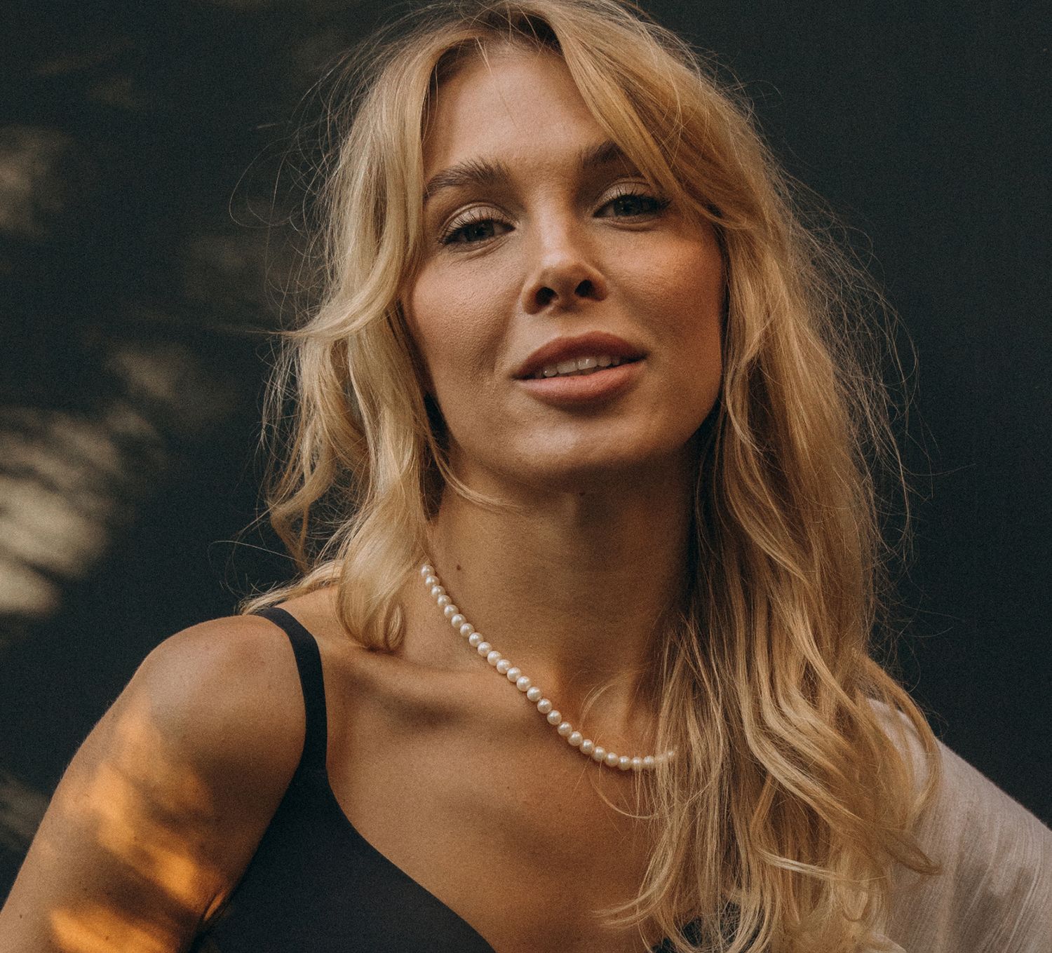 Blonde woman smiling with pearl necklace.