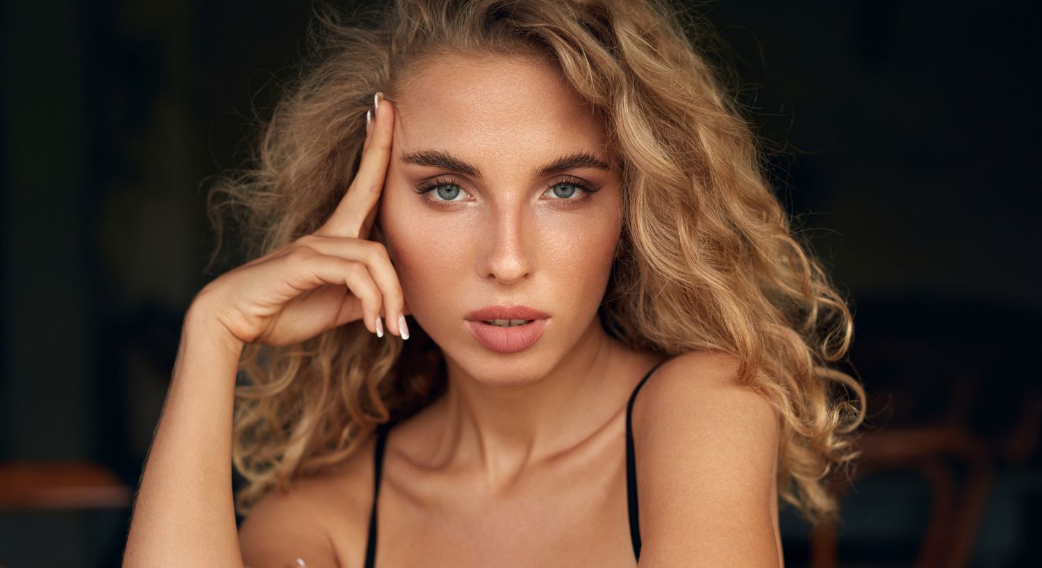 Woman with curly hair and thoughtful expression.